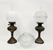 Two Victorian brass oil lamps with chimneys, one floral etched shade, the other white opaque