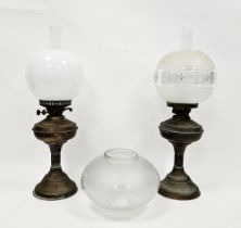 Two Victorian brass oil lamps with chimneys, one floral etched shade, the other white opaque