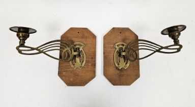 Pair of Art Nouveau brass wall lights each with pierced whiplash decoration, on later pine mounts,