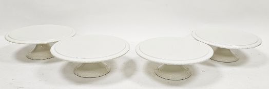 Four cream glazed pottery cake stands, of circular form, on spreading bases, 28.5cm diam. (4)