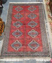 Turkish-style red ground wool rug, central panel with two rows of five geometric stepped lozenges in