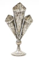 Continental white metal three flute posy vase, decorated throughout with embossed village scenes and