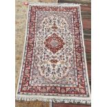 Indian cream ground wool pile rug, central floral medallion within stylised floral panel with