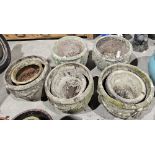 Five large weathered composite stone plant pots, one bearing swag decorations, the others bearing