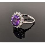 18ct gold, amethyst and diamond cluster ring, the oval amethyst 11.9mm x 9.9mm x 6.4mm deep