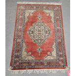 Eastern red ground silk rug, possibly Iraq, the central lozenge medallion depicting flowers and