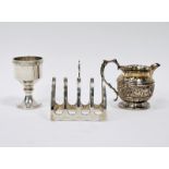 Early 20th century silver four-slice toast rack, an embossed silver cream jug and a silver egg cup