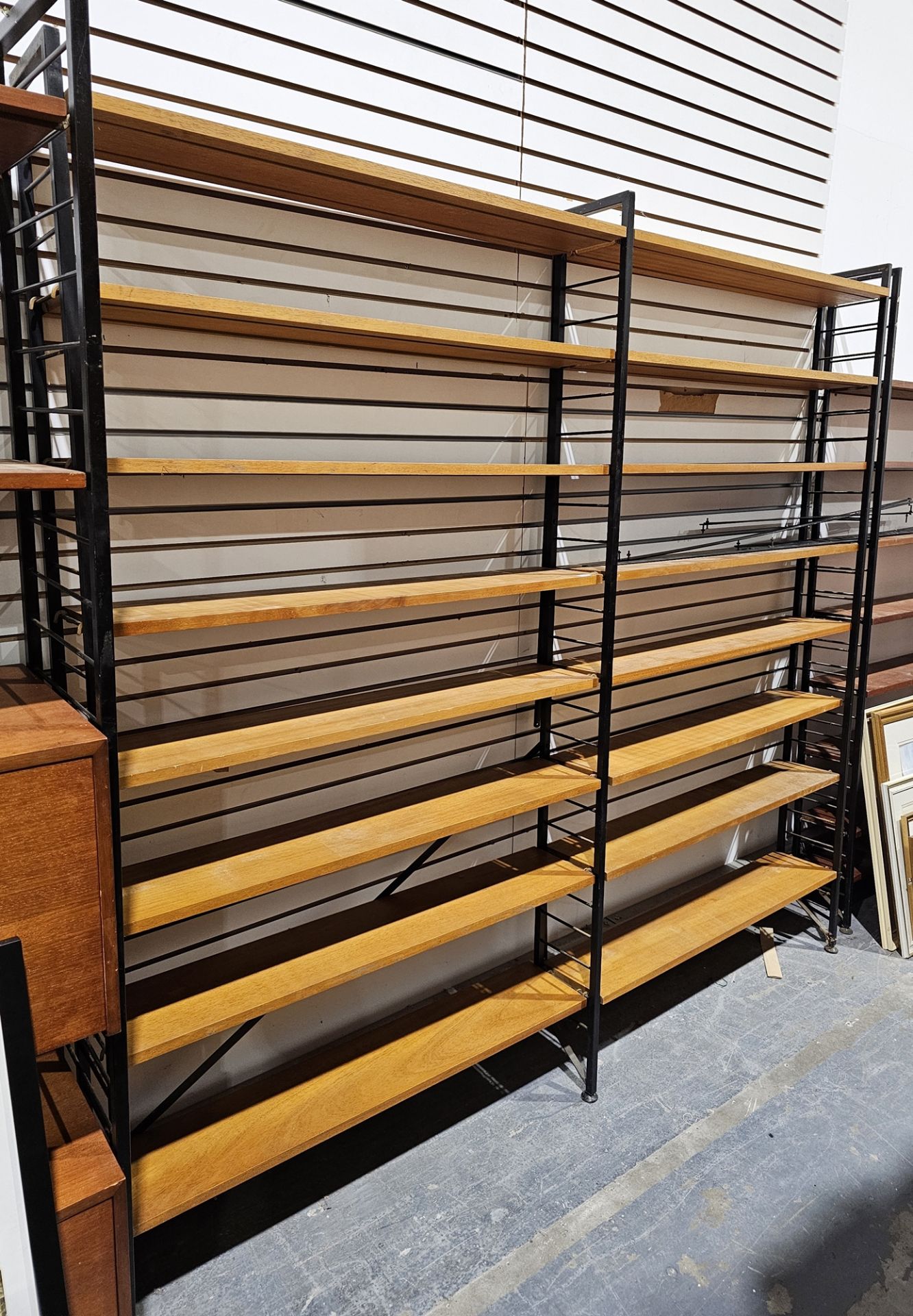 Mid century Ladderax three-section shelving unit comprising three black painted metal frames and