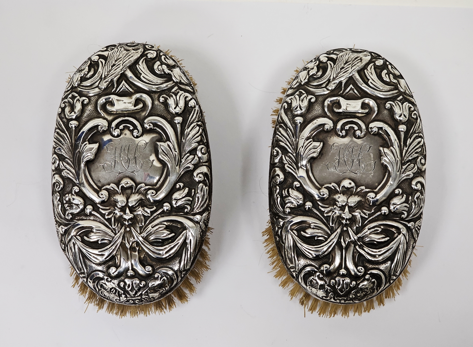 Pair of Victorian silver backed oval clothes brushes, each in repousse with masks and scrolling