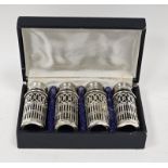 A set of four silver plated pepperettes, on a pierced lattice decoration, blue glass liners, in