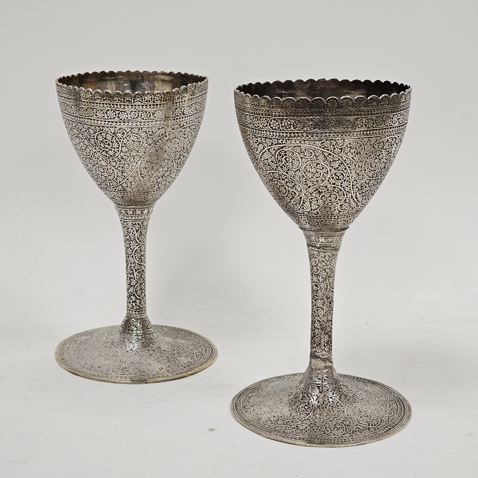 Pair Indian silver coloured metal goblets, with scalloped rim allover chased with flowerhead and