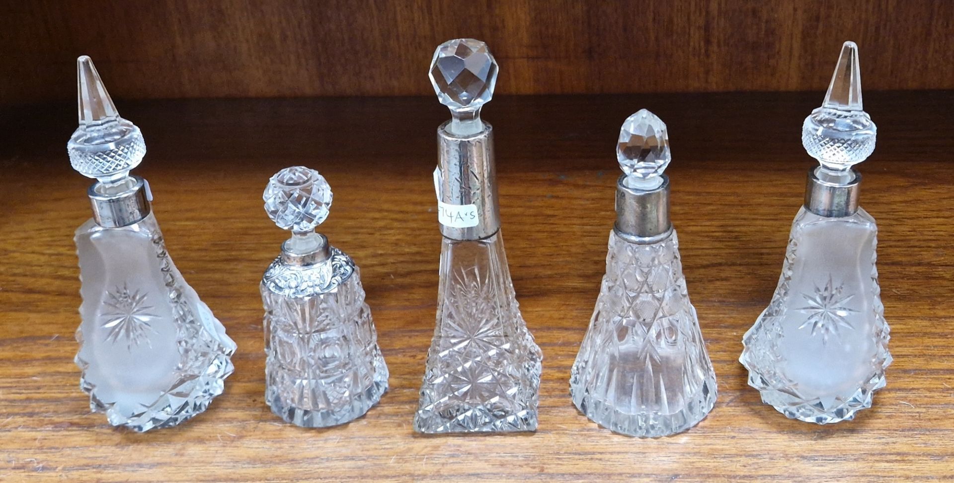 Four Victorian and Edwardian silvered collared cut-glass perfume bottles and a white metal mounted