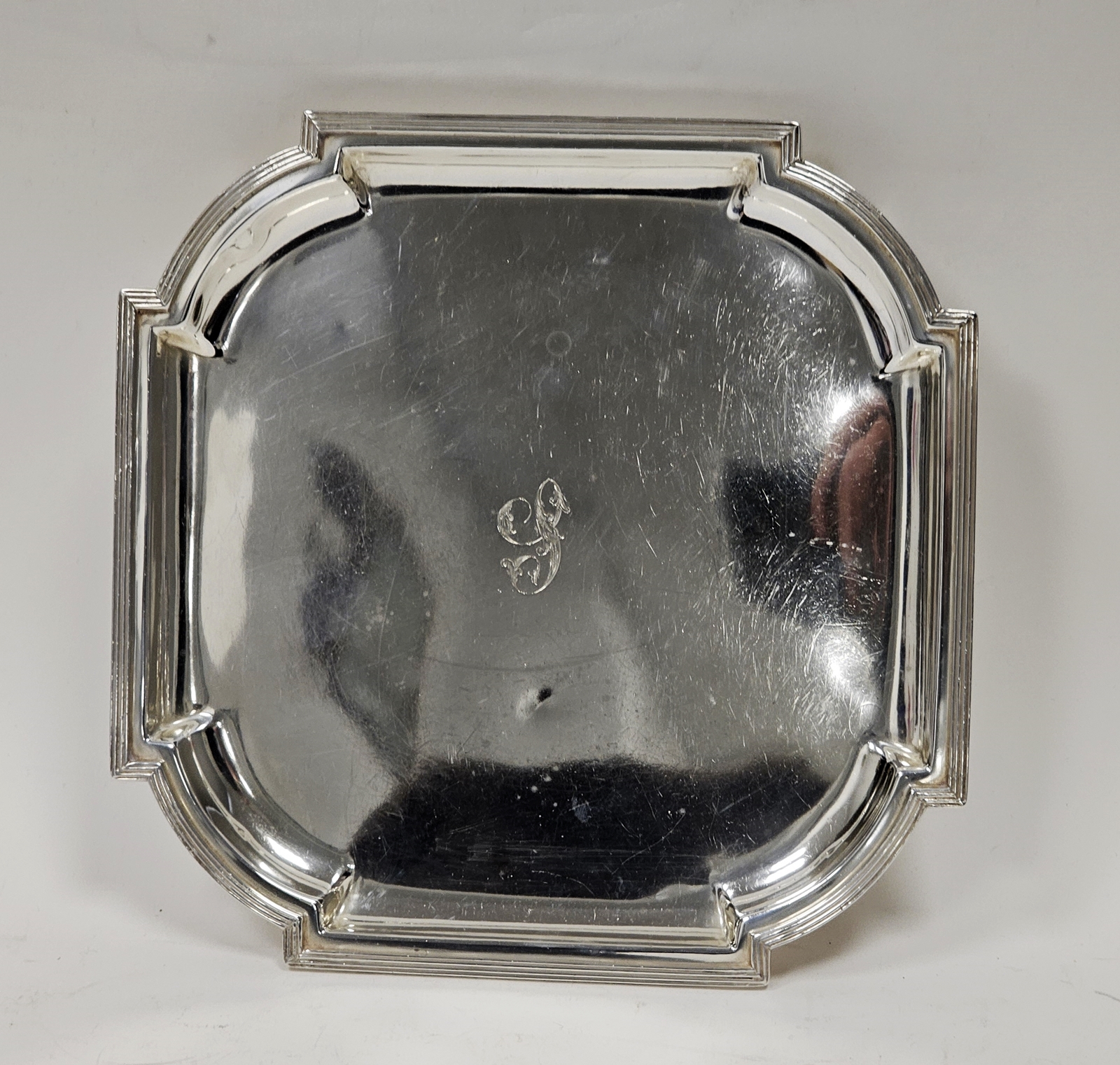 A George V silver shaped square salver, reeded border, raised on four scroll legs, approximately