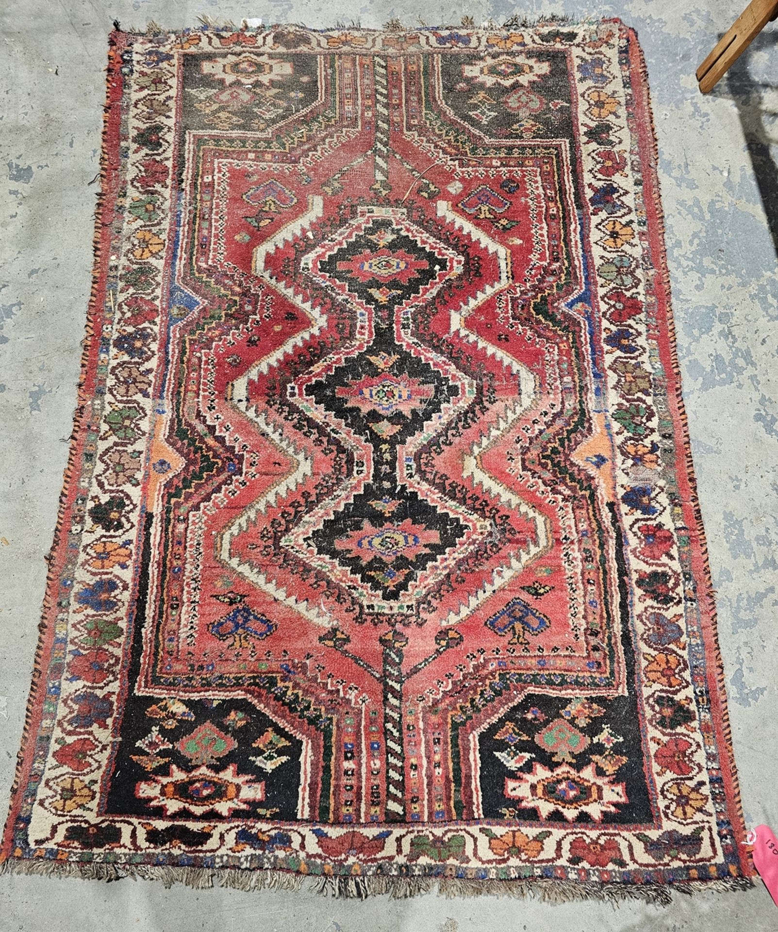 Eastern red ground rug with central three stepped lozenge medallion on geometric shape field to