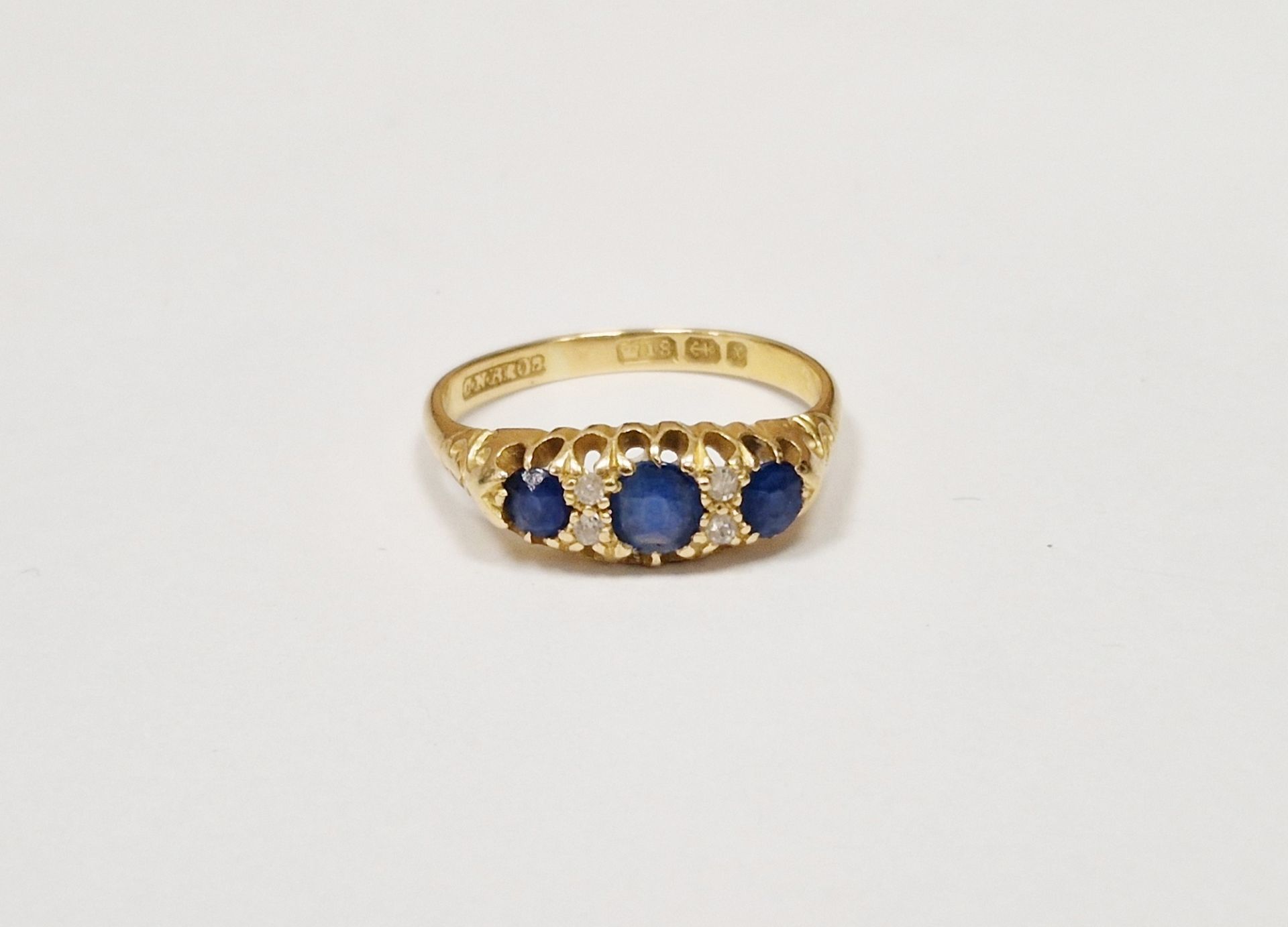 18ct gold, sapphire and diamond ring set three graduated sapphires alternating with two pairs tiny