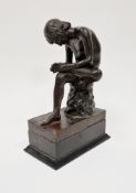 Bronze figure of a seated young nude male , looking at the sole of his left foot, blindstamp foundry