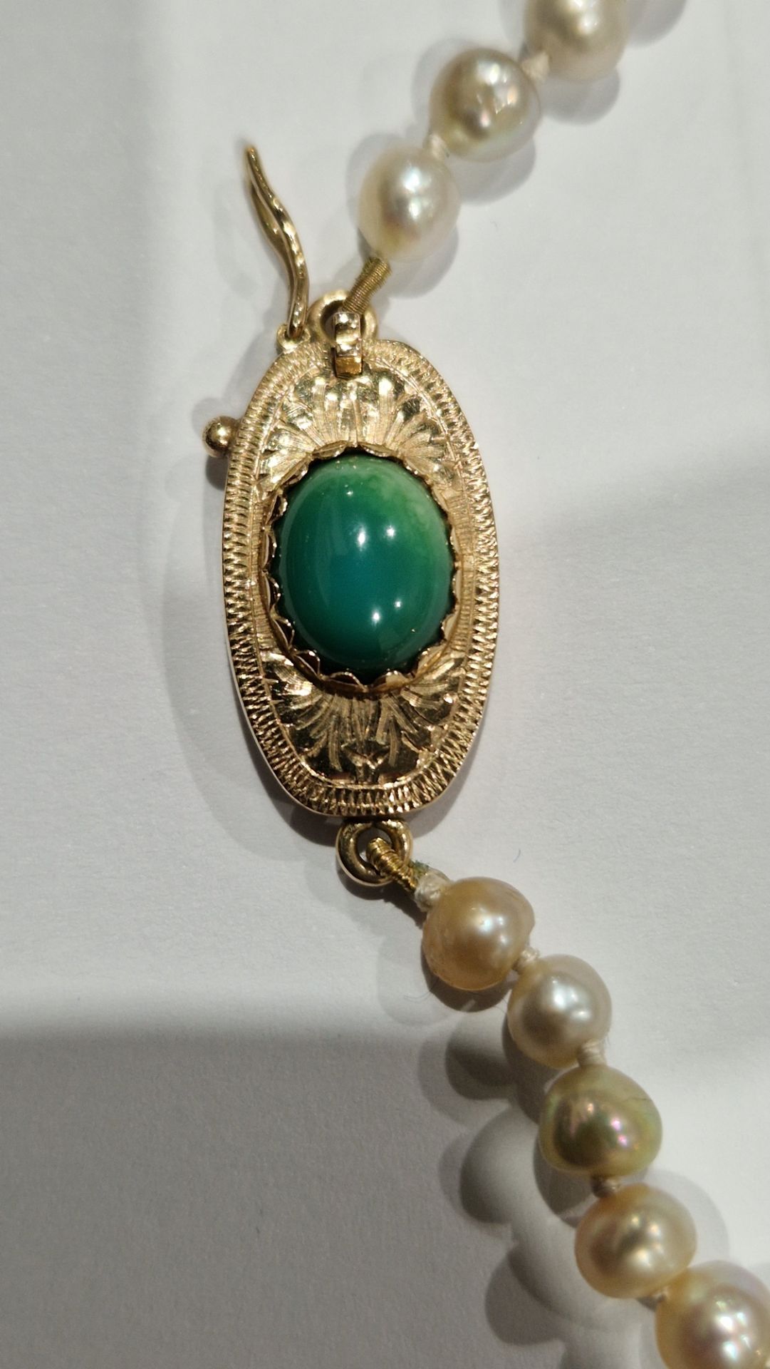 String of graduated freshwater pearls on 18ct gold and jade set oval clasp with foliate engraving, - Image 2 of 2