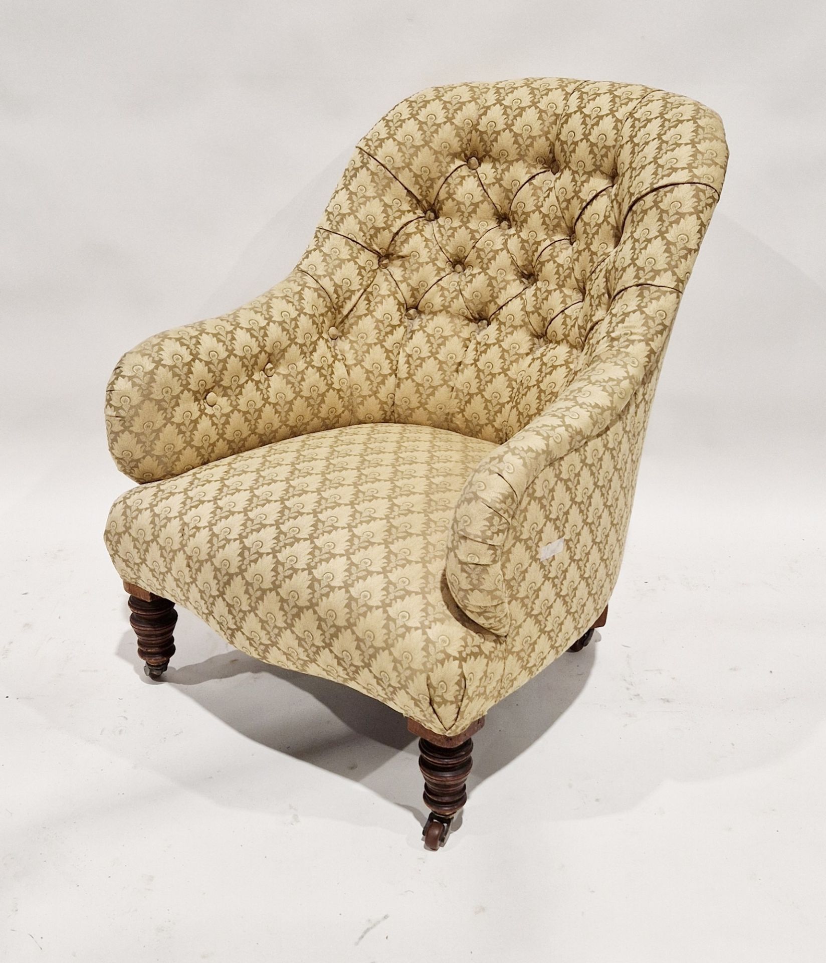 Late 19th/early 20th century buttonback armchair upholstered in yellow floral fabric, on castors,