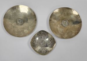 A pair of South African silver-coloured metal circular footed dishes, both inset with a 1969 one