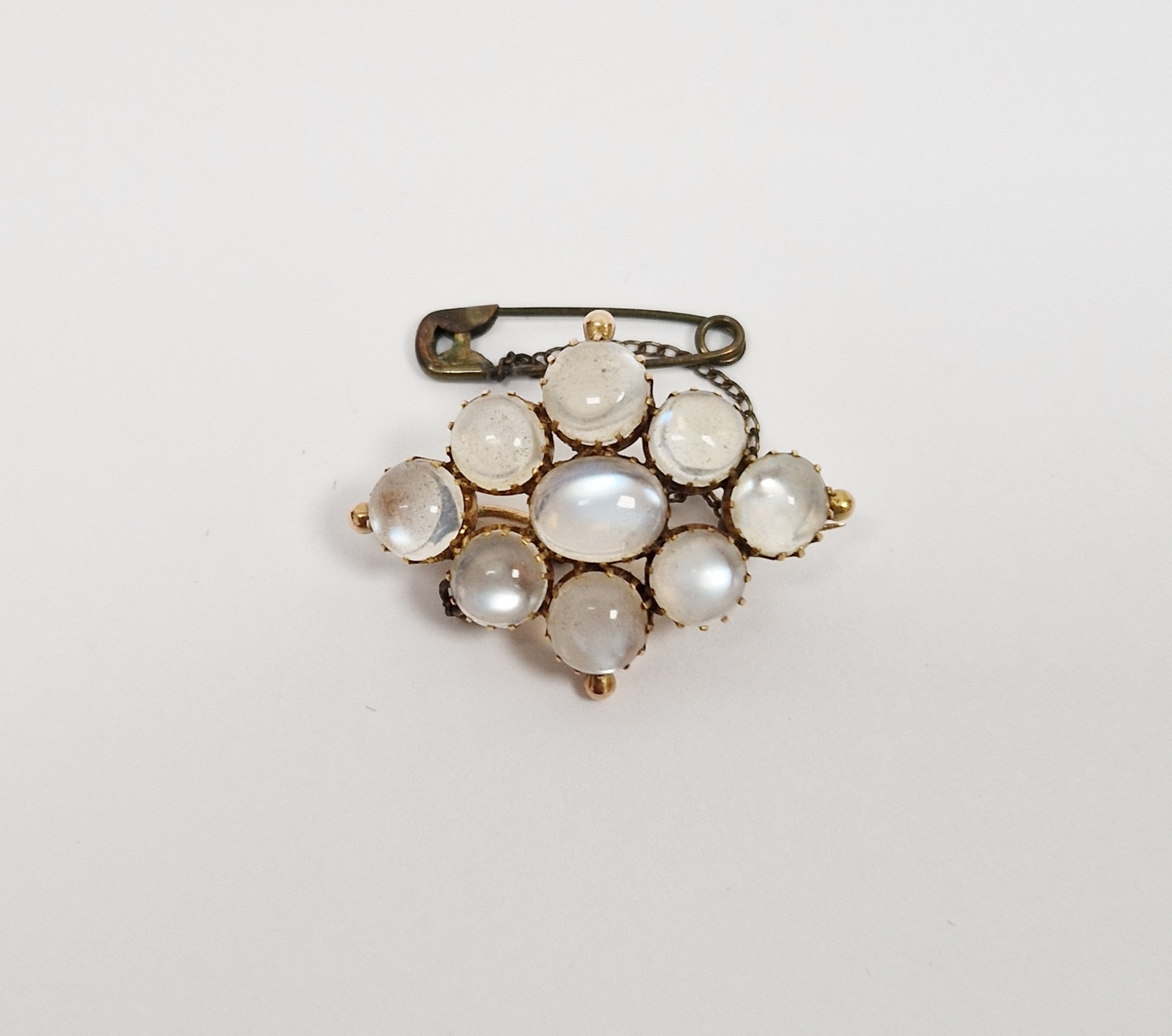 Gold-coloured metal and moonstone brooch, lozenge-shaped, having central oval stone surrounded by