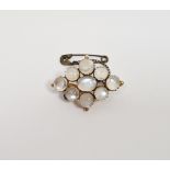 Gold-coloured metal and moonstone brooch, lozenge-shaped, having central oval stone surrounded by