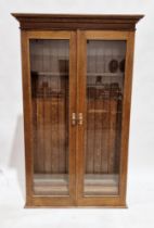 20th century oak glazed gun cabinet, the two doors opening to reveal slots of eight guns, over two