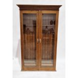 20th century oak glazed gun cabinet, the two doors opening to reveal slots of eight guns, over two