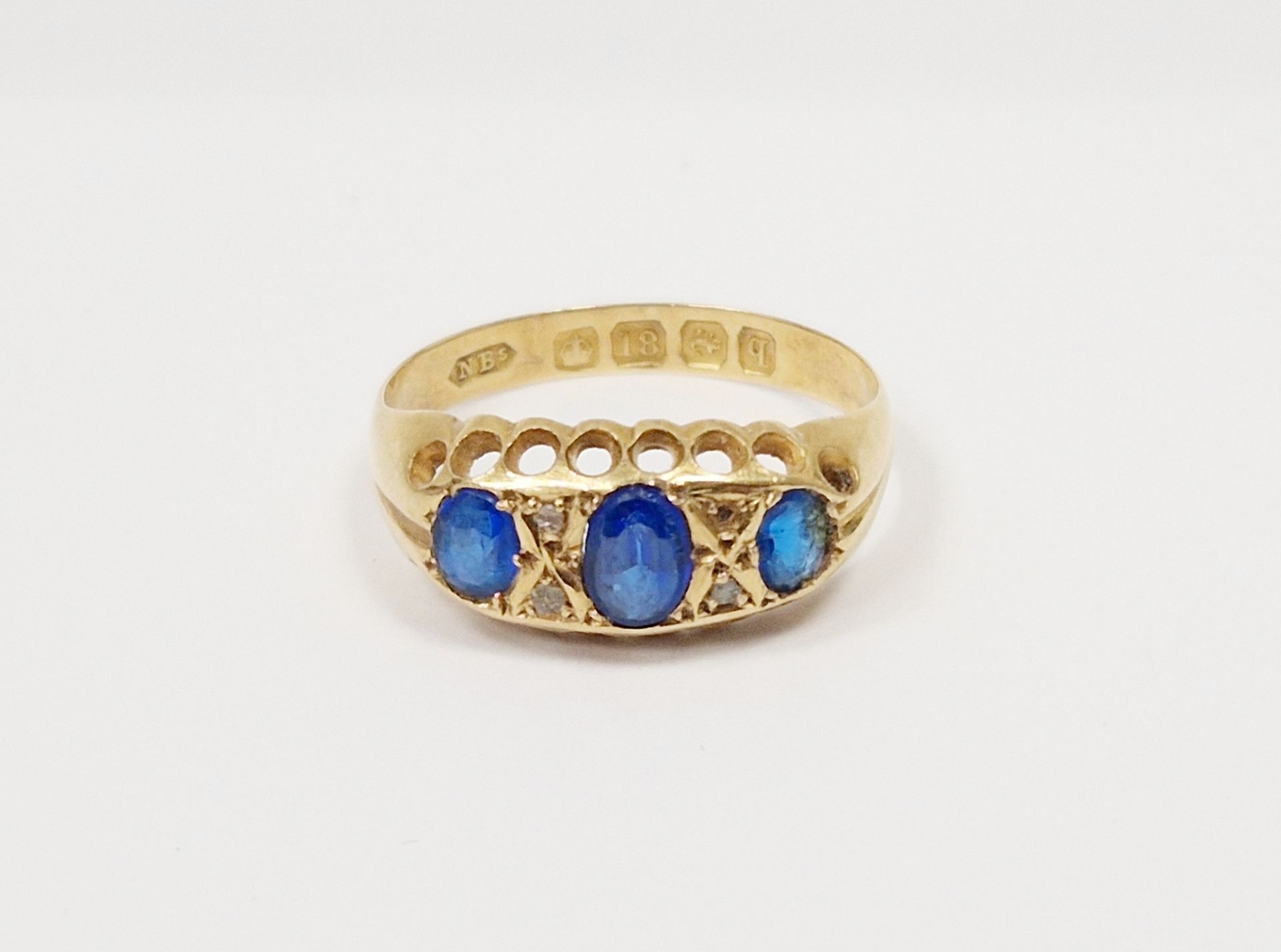18ct gold and blue stone ring set three oval facet-cut graduated stones alternating with four tiny