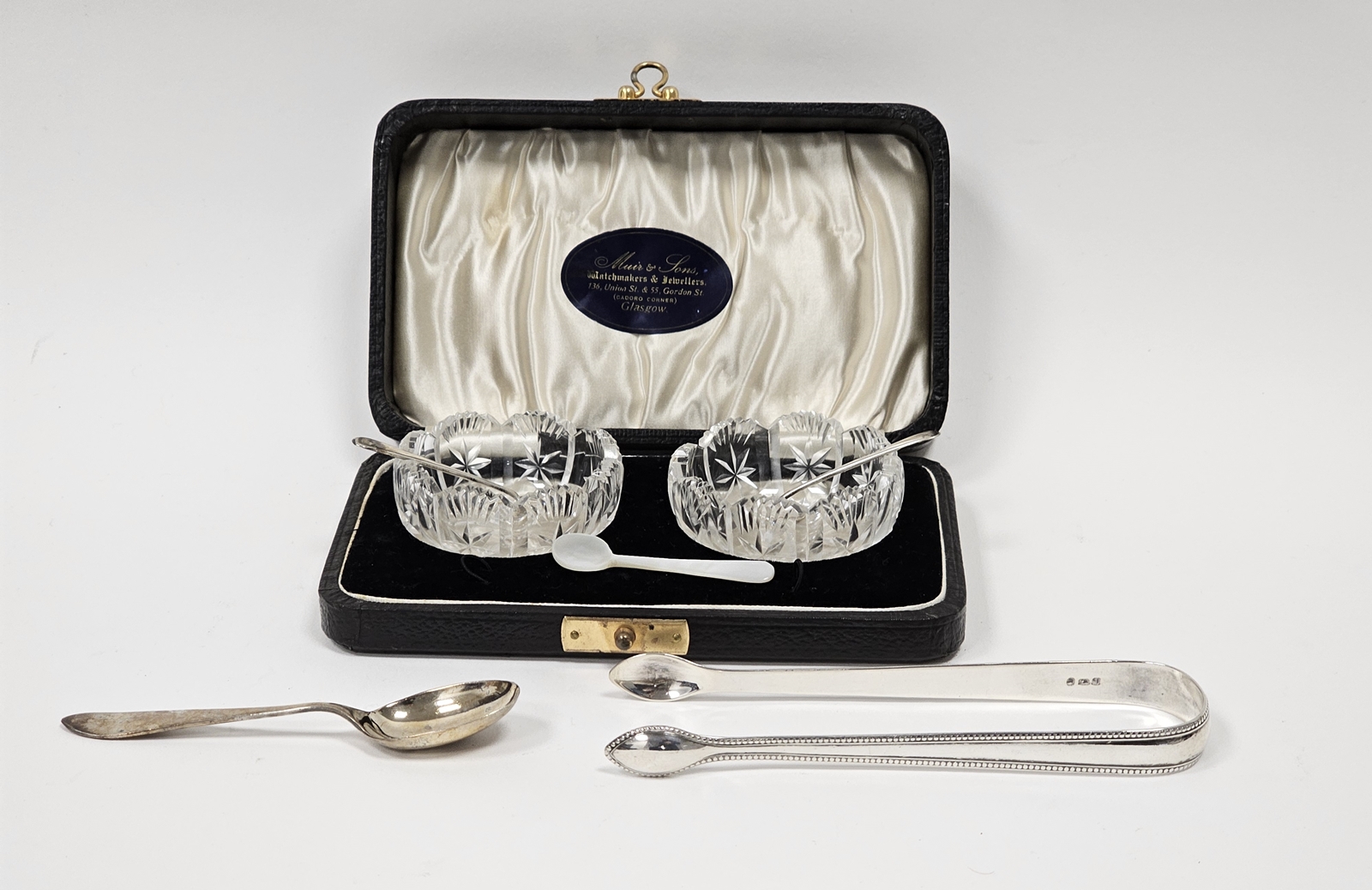Cased pair of cut glass salts and silver salt spoons, case bearing label for Muir & Sons, Glasgow, a