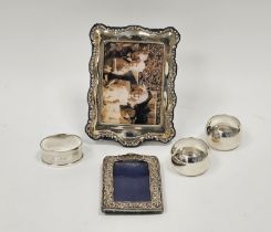 Three various silver napkin rings, silver photograph frame, rectangular with scroll and foliate