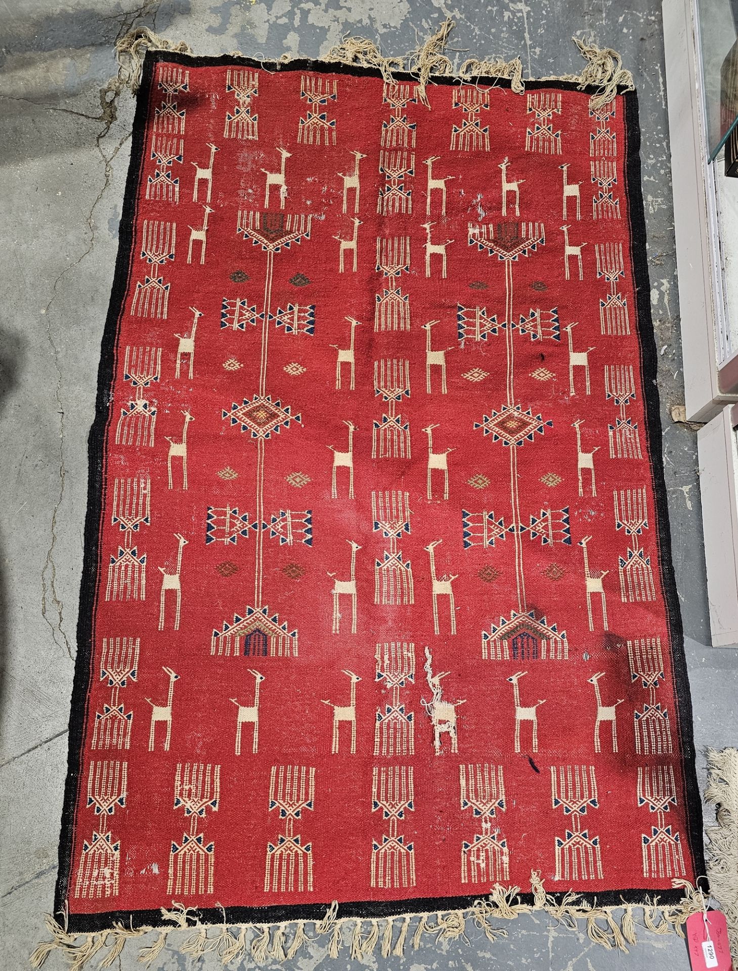 Red ground rug with stylised animal and geometric pattern with single black border, 150cm x 97cm