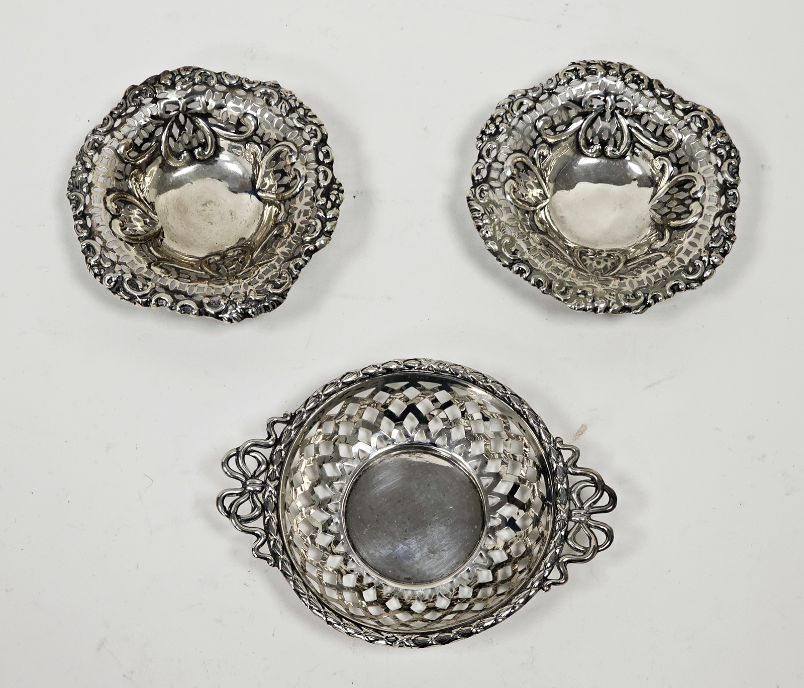 A pair of Victorian silver pierced circular bonbon dishes, embossed with heart motifs, raised on
