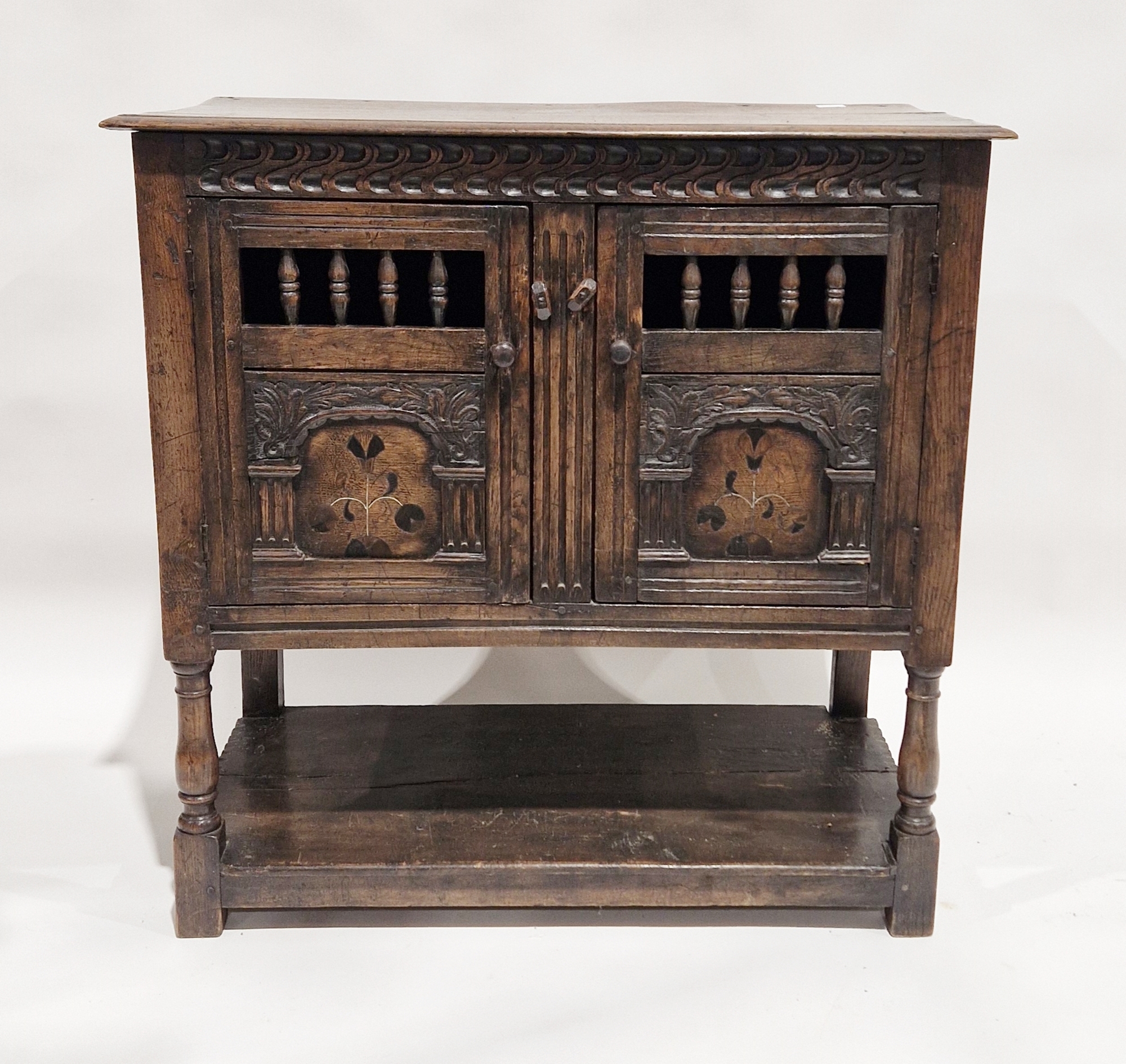 18th century oak dole cupboard, the two cupboard doors with turned spindle sections, carved and