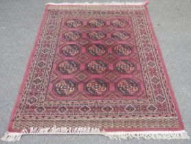 Eastern wool rug with maroon field, having five rows of three elephants foot guls, geometric