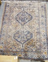 Eastern wool rug of caucasian design with two stepped octagonal blue medallions to the madder field,