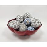 Quantity of printed ceramic spheres with scroll and stylised floral decoration in red lacquered bowl