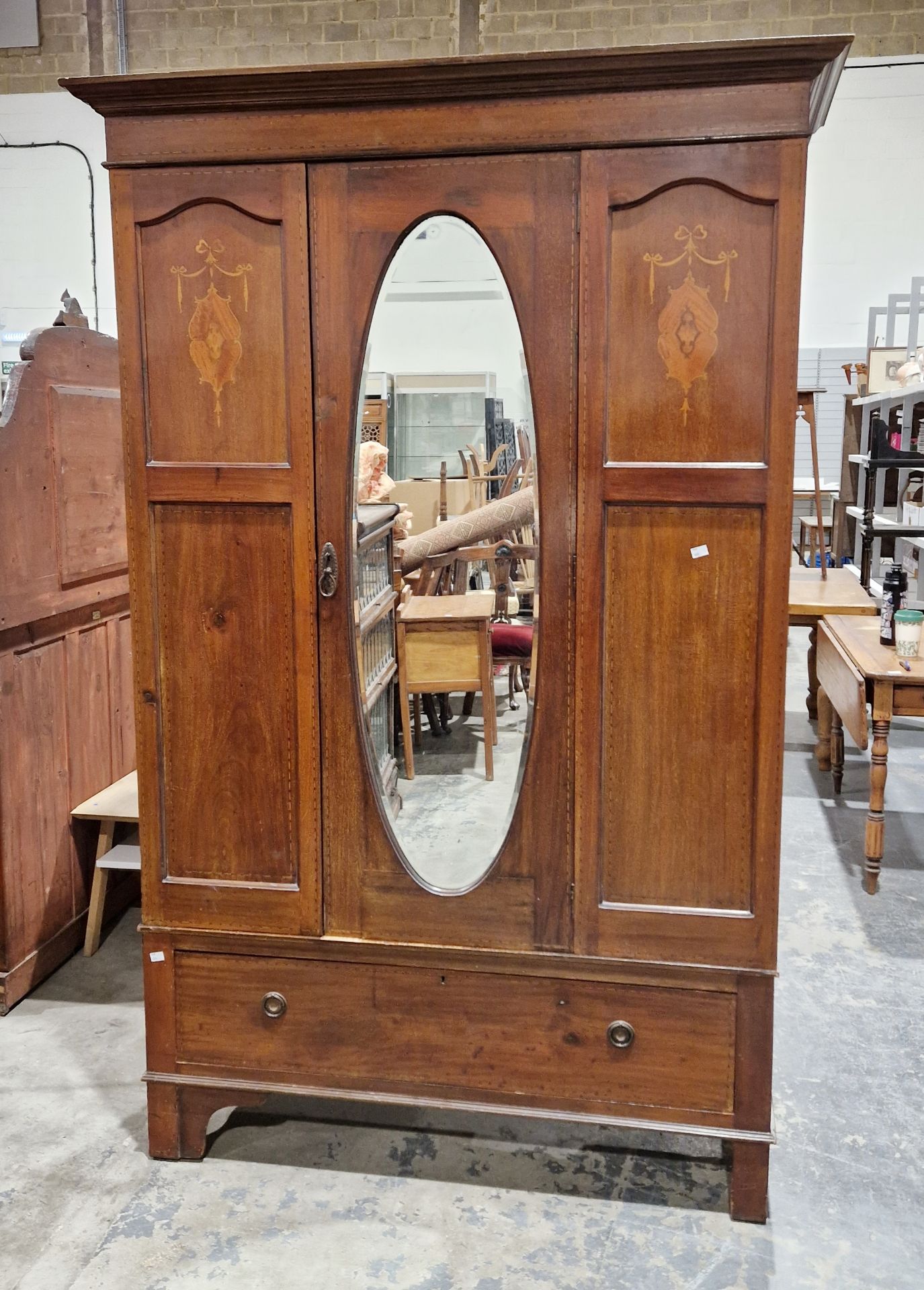 Edwardian mahogany single door wardrobe, the door with oval bevel edged mirror, inlaid marquetry and