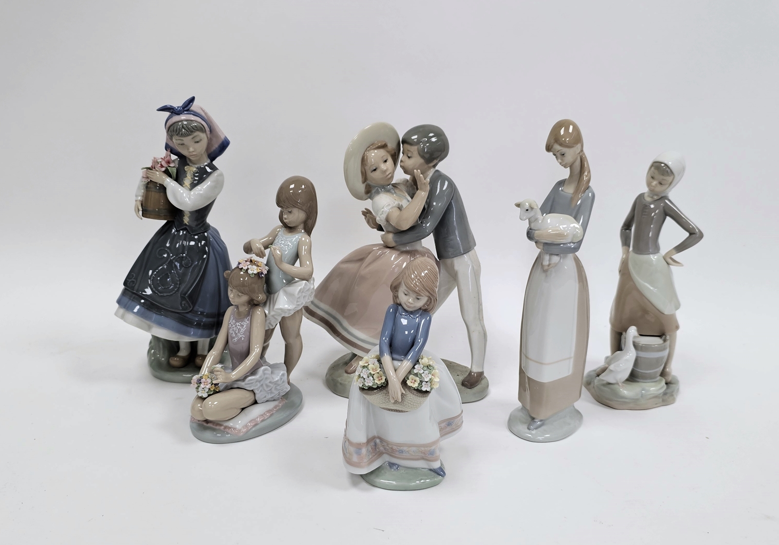 Six Lladro figures including a boy kissing a girl, little girl holding a basket of flowers,