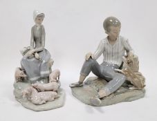 Lladro figures of a boy with dog and a girl with piglets, each modelled seated on rockwork,