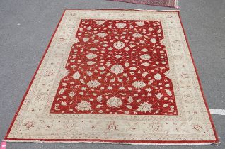 Large Eastern wool carpet of revived Persian design, having swollen flowerheads to the rust field,