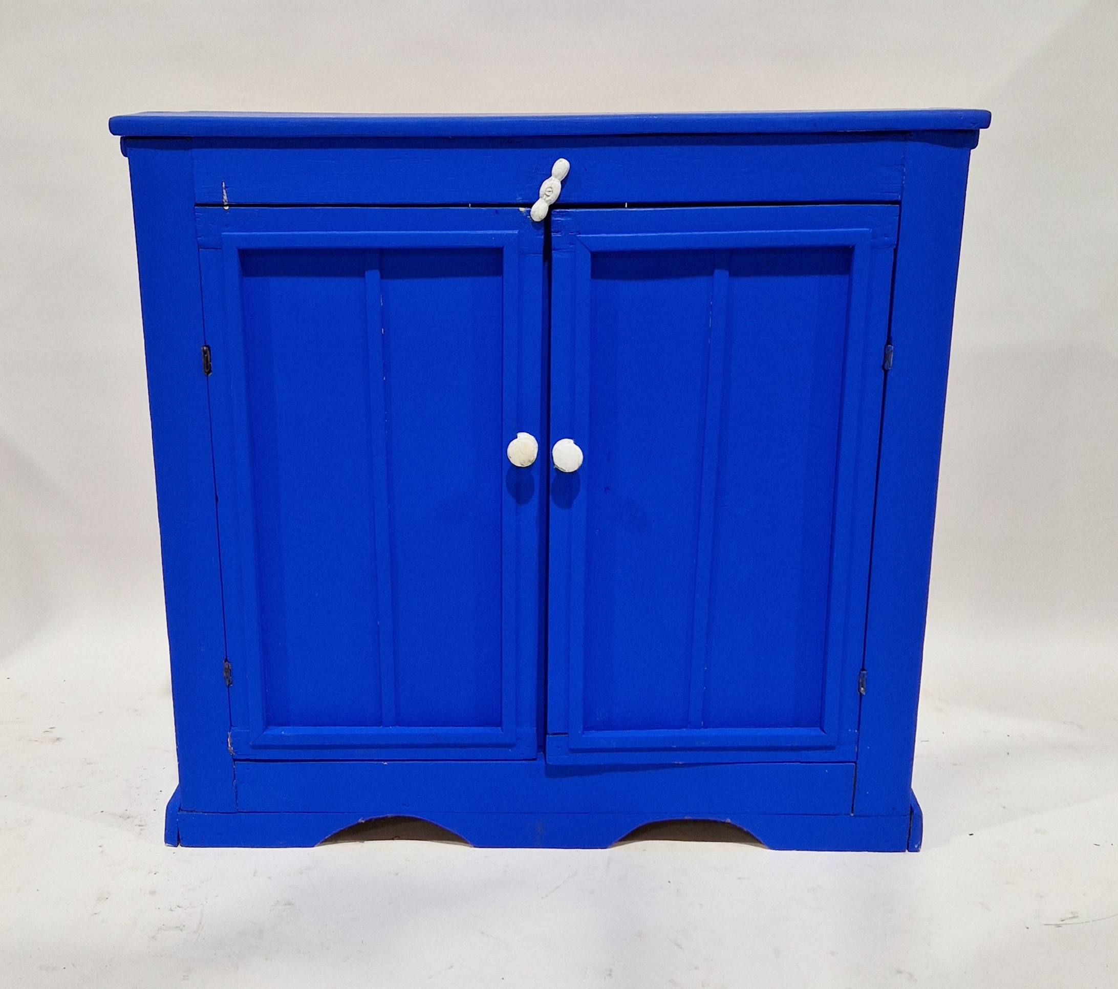 Vintage blue painted kitchen cupboard with two panelled doors revealing a single shelf, with