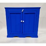 Vintage blue painted kitchen cupboard with two panelled doors revealing a single shelf, with