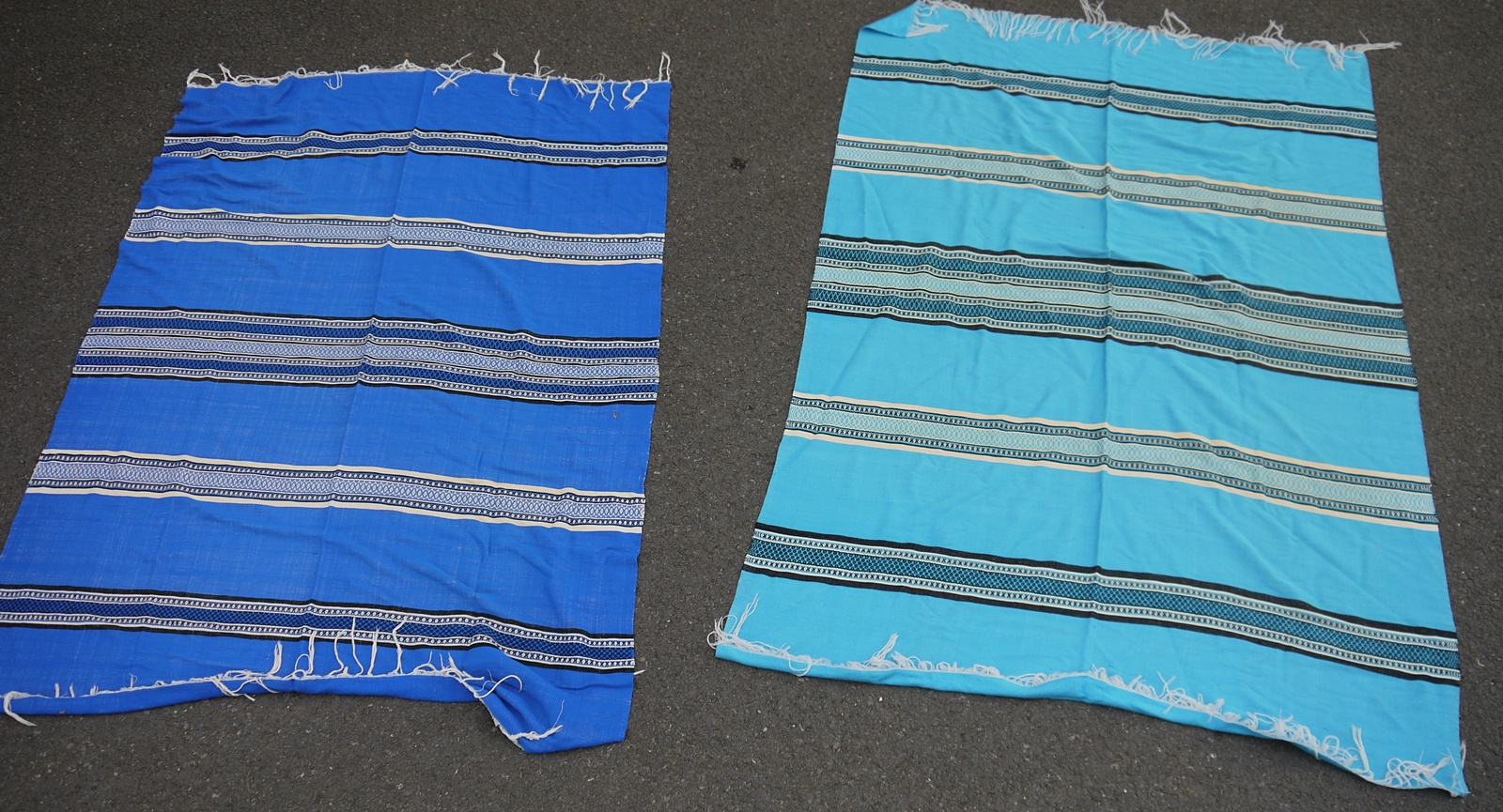 Two similar fringed throws in shades of blue with geometric designs (2)