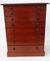 Stained wood apothecary's cabinet having eight graduated drawers with bun handles, containing