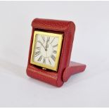 Dunhill gilt metal and leather travel clock, the square face with Roman numerals, in red leather