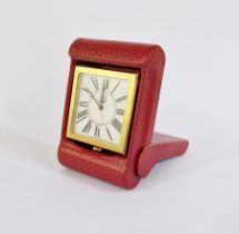 Dunhill gilt metal and leather travel clock, the square face with Roman numerals, in red leather