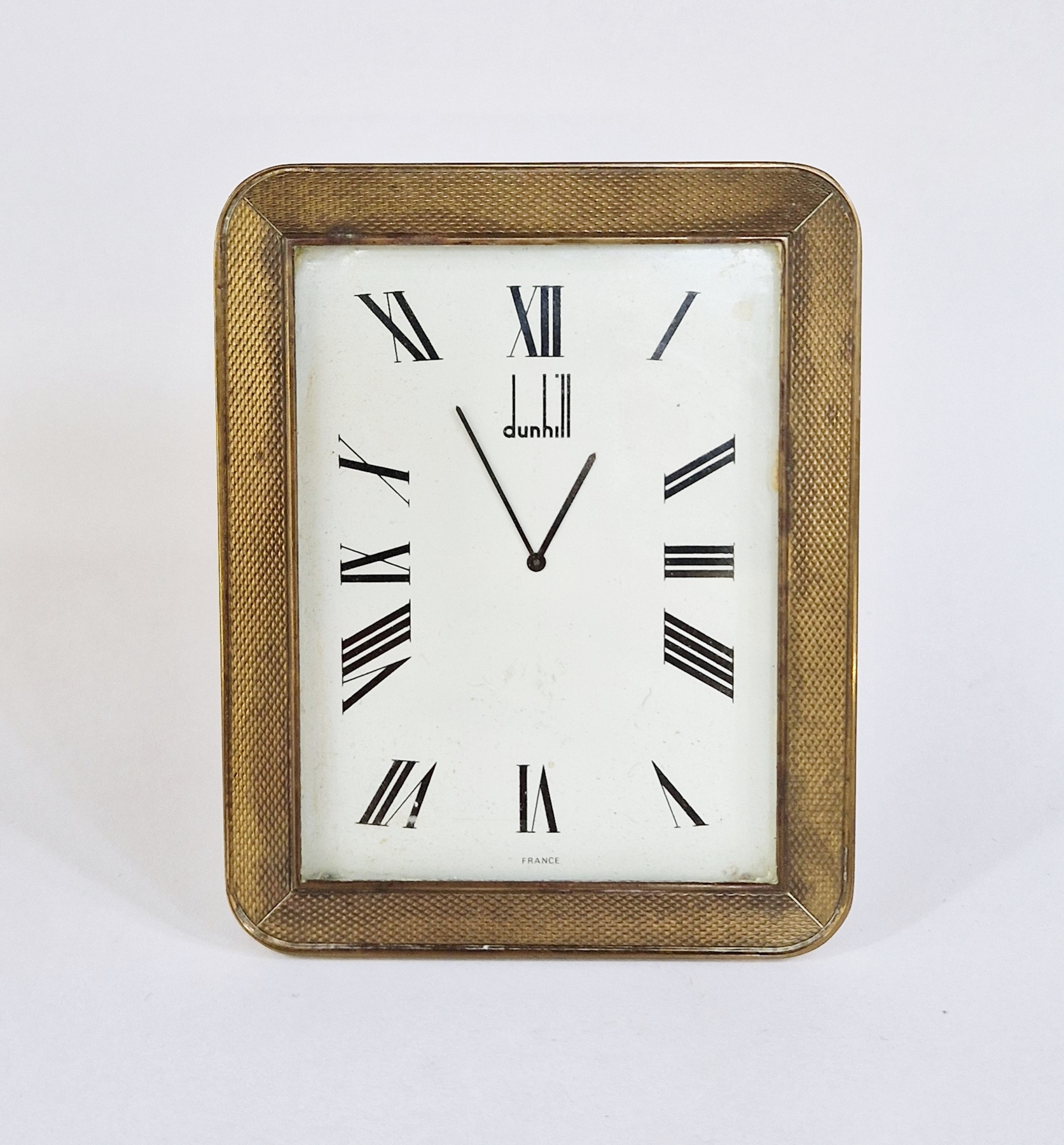 Dunhill brass desk clock, rectangular with rounded corners, engine-turned frame to the white
