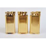 Three Dunhill gilt metal lighters with engine-turned decoration, no.120917, 45787 and 34677, each