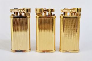 Three Dunhill gilt metal lighters with engine-turned decoration, no.120917, 45787 and 34677, each