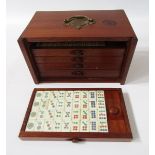 Bone and wood mahjong set with instruction booklet, in stained wood five-drawer table top cabinet